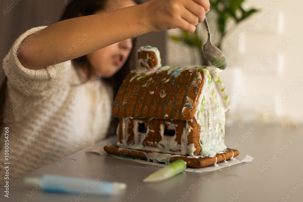 Little girl decorating gingerbread house for Christmas Little girl decorating gingerbread house for Christmas