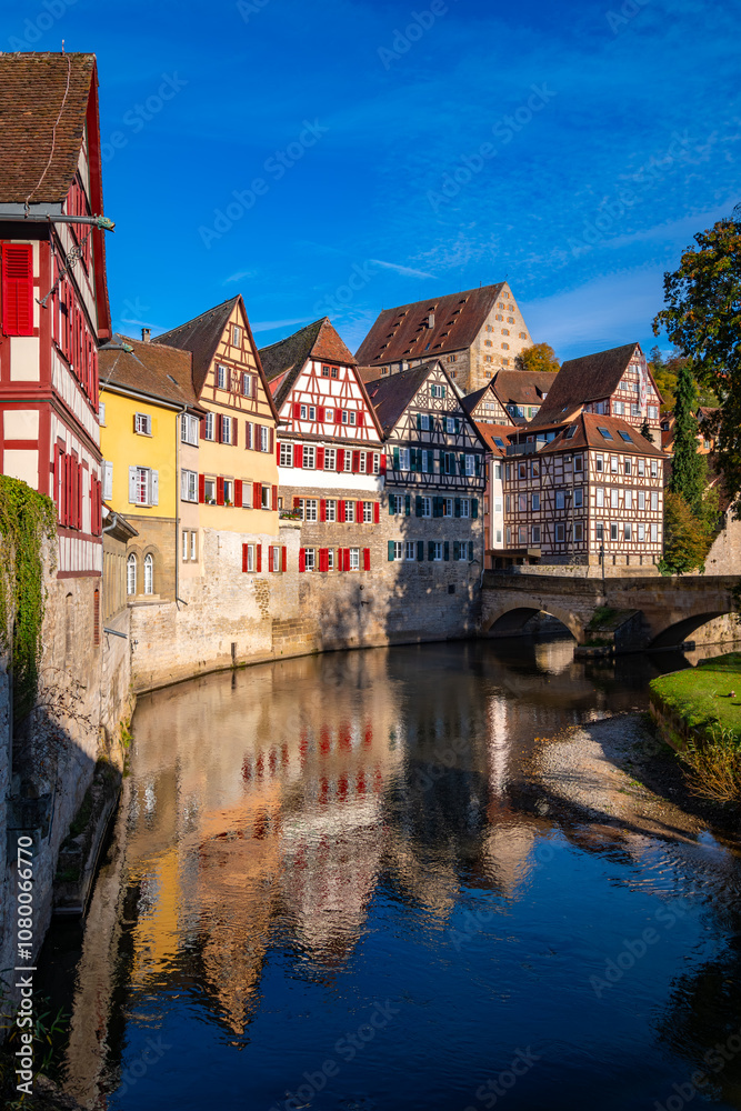 Naklejka premium Schwäbisch Hall is a picturesque small town in Baden-Württemberg (Germany). Historic old town buildings with colorful half-timbered facades and a stone bridge are reflected in River Kocher in autumn.