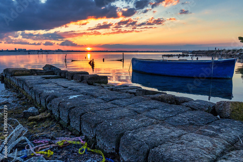 Tramonto con barche tradizionali sul Mar Piccolo di Taranto - Puglia, Italia photo