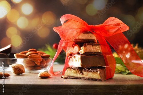 Chocolate covered nougat stacked with ribbon on golden bokeh background