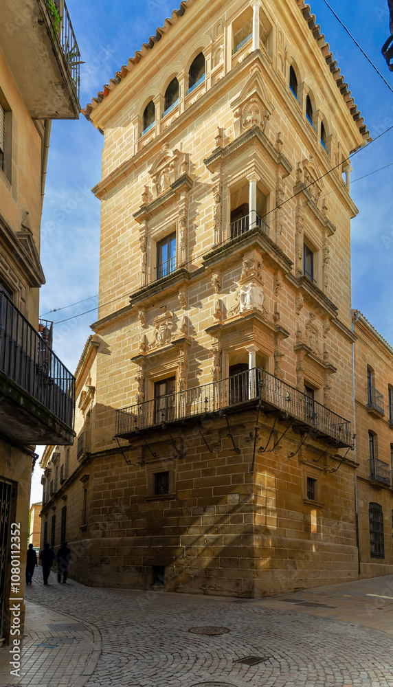 Streets of the city of Ubeda. A stone building with a large tower divides an alley into two narrower streets. Streets of the city of Ubeda. A stone building with a large tower divides an alley into two narrower streets.
