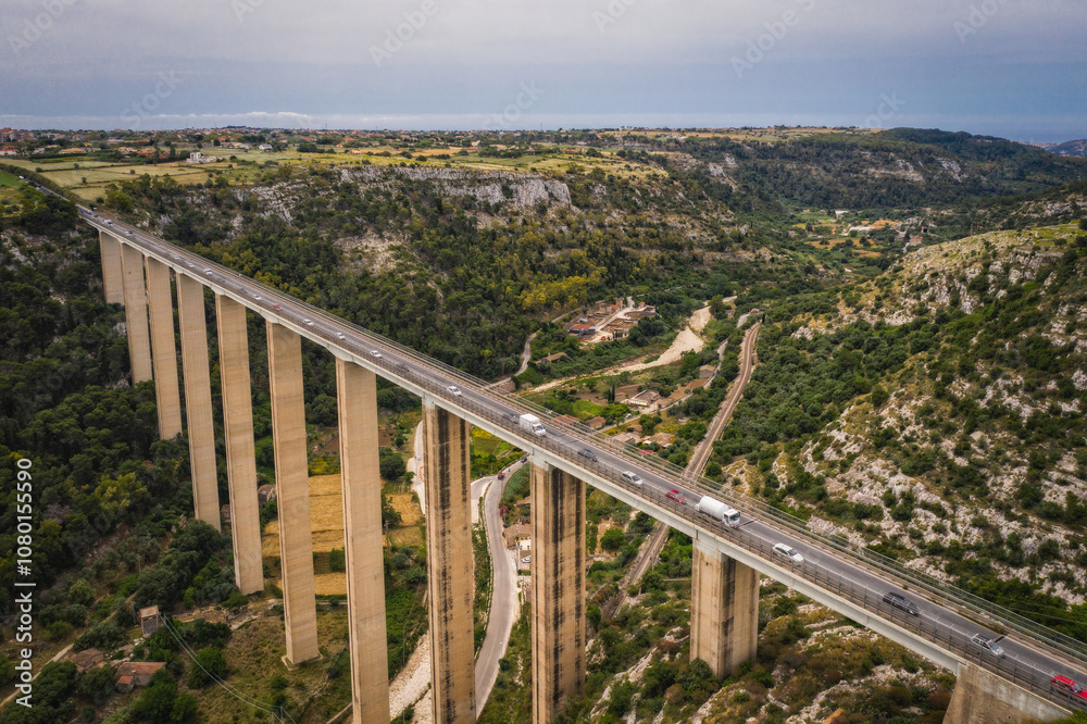 June 2023. Aerial landscape with panoramic view of the famous road viaduct Ponte Guerrieri on the 115 South Western Sicula state road and Modica Bassa in Ragusa Sicily, Italy. June 2023. Aerial landscape with panoramic view of the famous road viaduct Ponte Guerrieri on the 115 South Western Sicula state road and Modica Bassa in Ragusa Sicily, Italy.