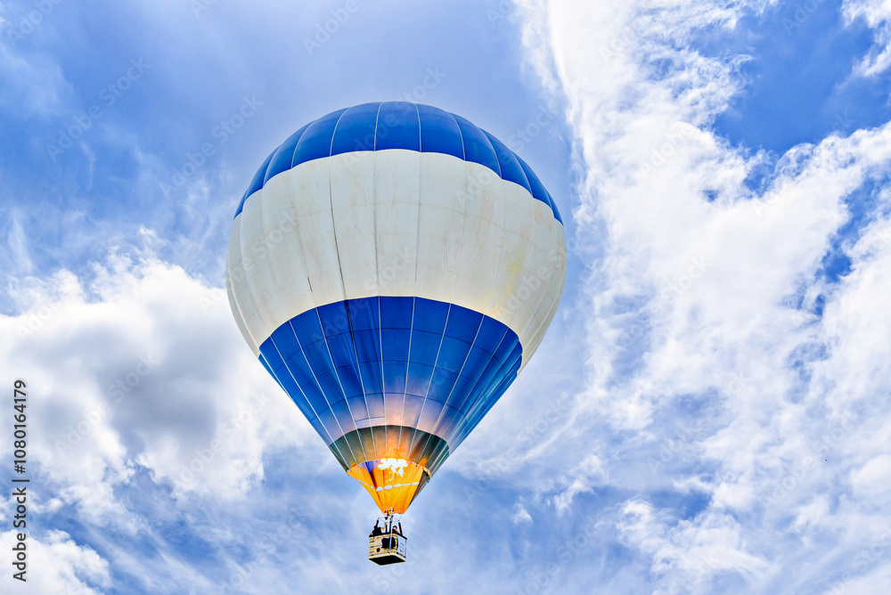 Obraz premium Colorful hot air balloon flying over blue sky with white clouds 