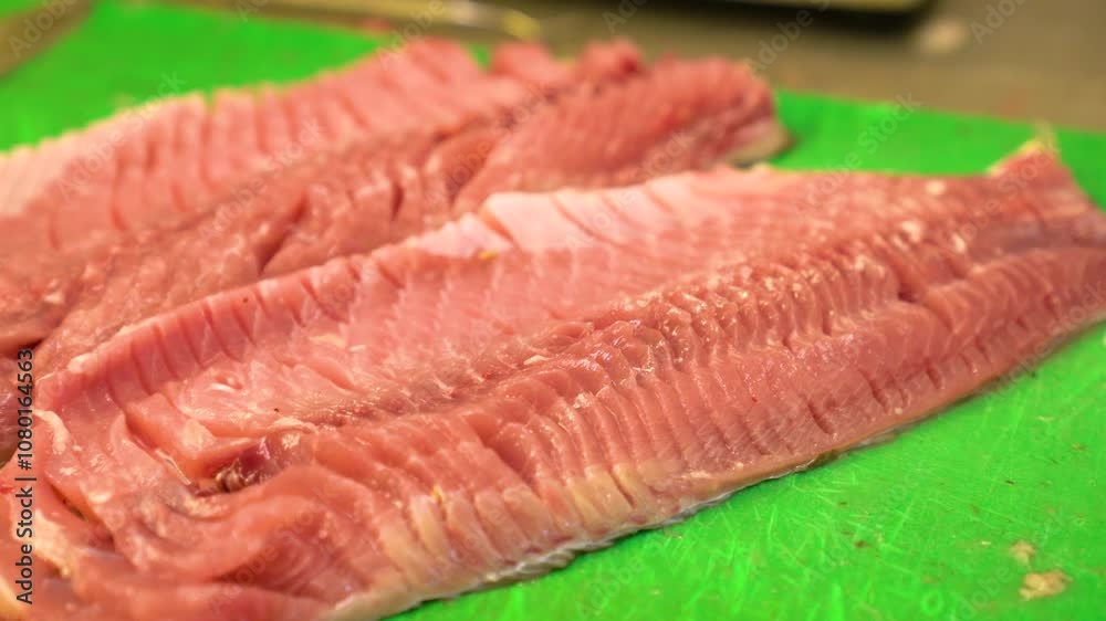 Fresh Sziki carp fillets displayed on a bright green cutting board in a kitchen setting Fresh Sziki carp fillets displayed on a bright green cutting board in a kitchen setting