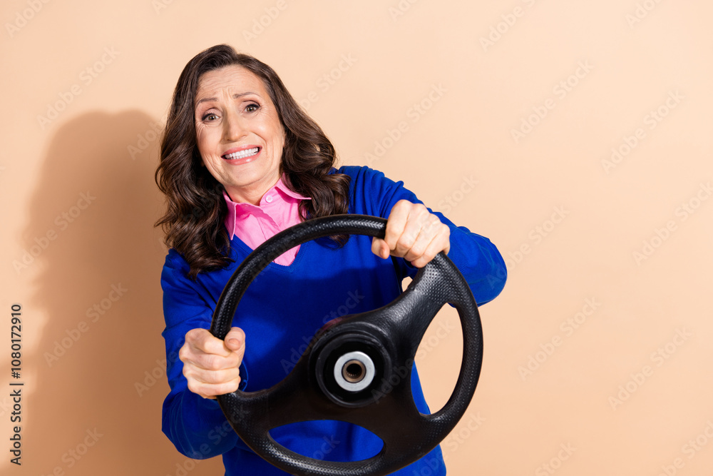 Photo of charming funny retired woman wear blue trendy clothes drive car isolated on beige color background Photo of charming funny retired woman wear blue trendy clothes drive car isolated on beige color background