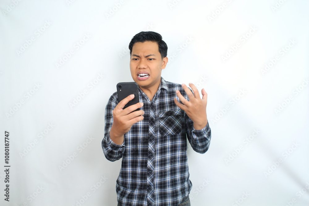furious asian man screaming holding smartphone with angry face wearing casual shirt isolated on white background furious asian man screaming holding smartphone with angry face wearing casual shirt isolated on white background