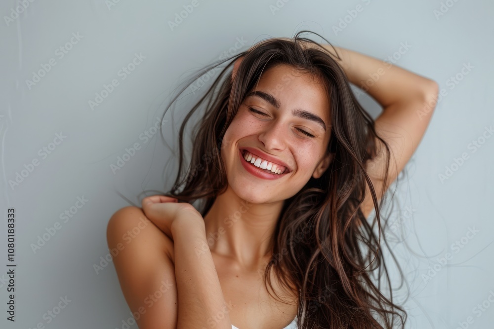 A woman, with long hair, exudes confidence and joy with a bright smile reflecting delight and contentment. She appears serene and graceful, showcasing a carefree and cheerful demeanor