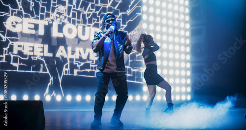 Portrait of an Energetic Hip Hop Artist in a Stylish Outfit Performing on Stage with a Young Female Dancer in Alternative Clothes. Standing in Front of a LED Screen with Dynamic Animation photo