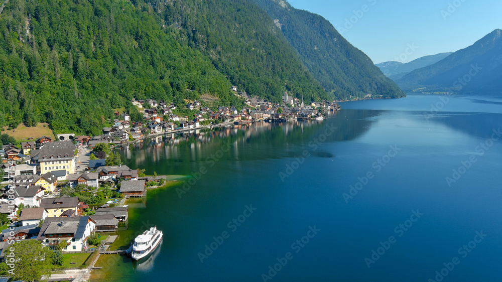 Fototapeta premium Tranquil Hallstatt lake scene with colorful village houses nestled by the water and surrounded by green mountains