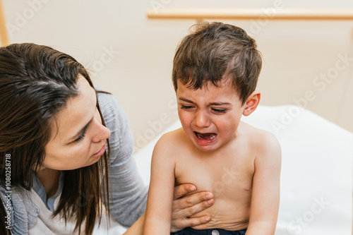 Physiotherapist comforting crying child during postural drainage therapy photo