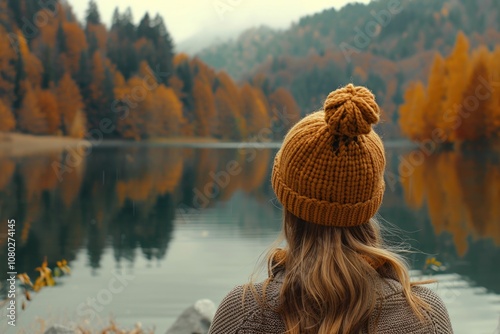 A woman wearing a knit hat looks out over a peaceful lake