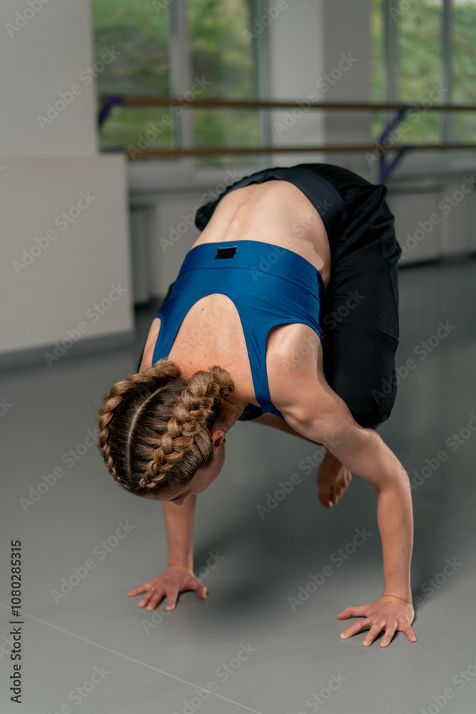 Naklejka premium in the spiritual development studio master class in yoga middle-aged girl in a blue top and pants in bright room pose asana strength exercises handstand only