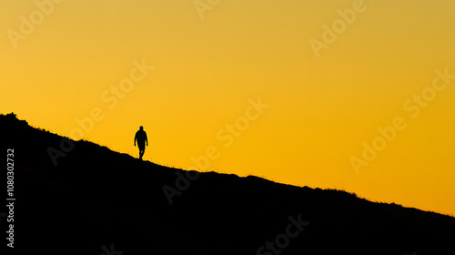 A sunrise hike with the silhouette of a lone hiker walking along a ridgeline as the sky turns golden.