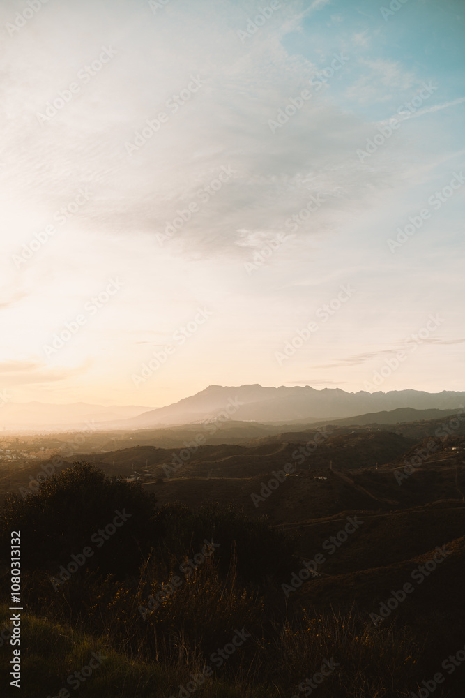 Softly lit hills and distant mountains under a golden sunset, creating a peaceful natural landscape Softly lit hills and distant mountains under a golden sunset, creating a peaceful natural landscape
