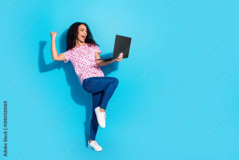 Full length photo of lucky lovely girl wear print t-shirt winning game modern gadget empty space isolated blue color background Full length photo of lucky lovely girl wear print t-shirt winning game modern gadget empty space isolated blue color background