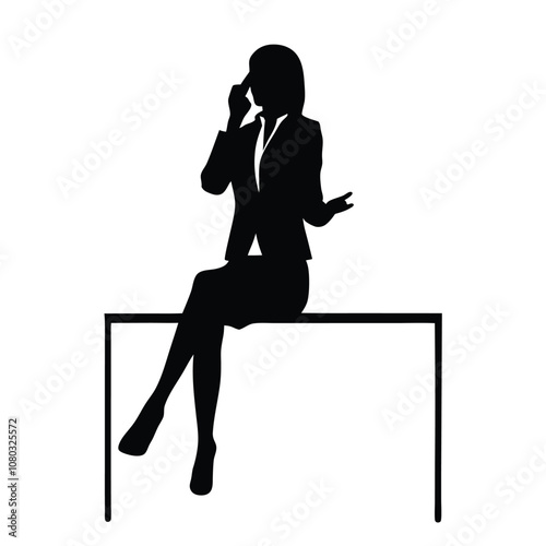 A woman is sitting at a desk with a laptop. She is talking on the phone