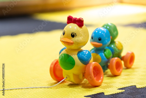 Pull-along duck toy for toddlers on yellow mat. Concept of fun and engaging playtime for kids photo