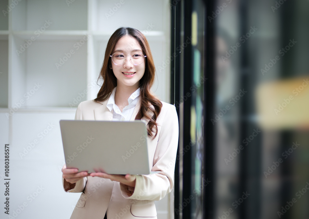 Businesswoman using a laptop and reviewing data with sticky notes in the background. Businesswoman using a laptop and reviewing data with sticky notes in the background.