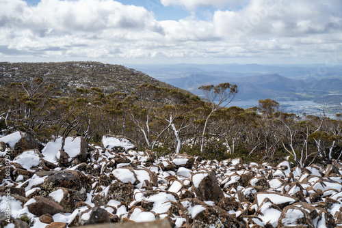 family's playing in snow on the peak of a rocky mountain in a national park looking over a city below, mt wellington hobart tasmania australia in summer. ice on the roads. roads closed photo