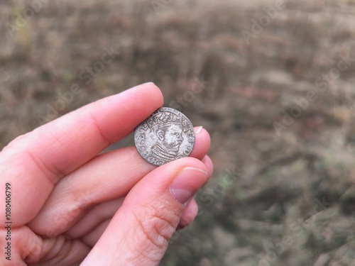 An ancient coin in your hands. An old silver coin photo