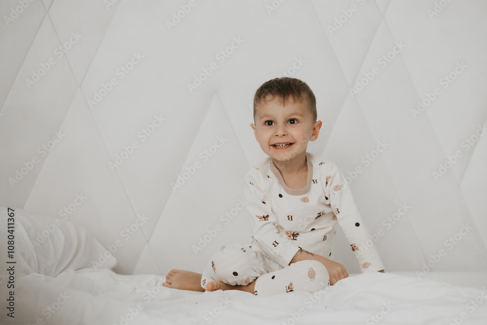 Smiling Child Sitting on Bed in Pajamas Smiling Child Sitting on Bed in Pajamas