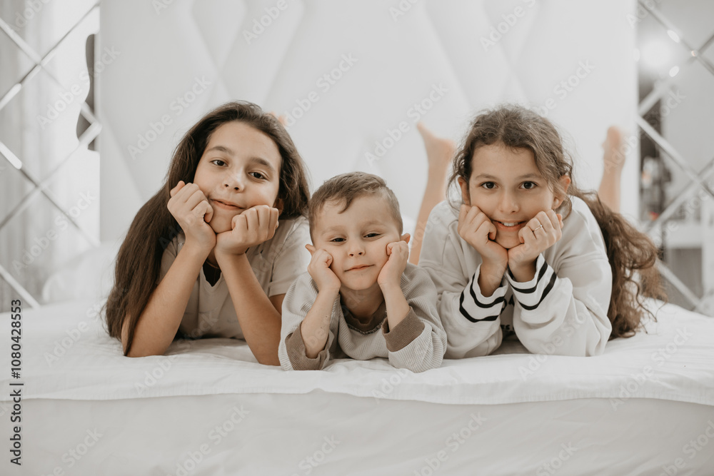 wo sisters and little brother lying together, sharing a joyful bond wo sisters and little brother lying together, sharing a joyful bond