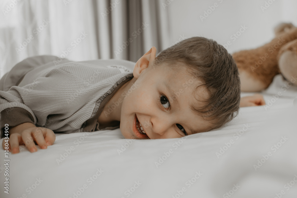 Smiling child lying on bed with playful expression Smiling child lying on bed with playful expression