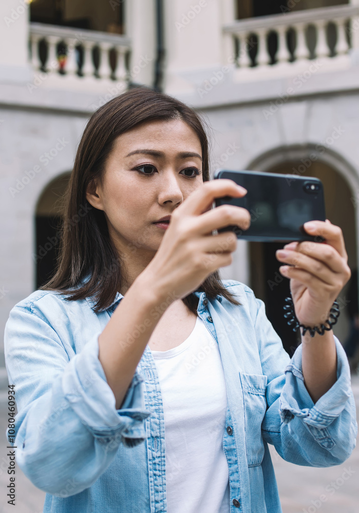 Focused beautiful Asian tourist taking photo with smartphone Focused beautiful Asian tourist taking photo with smartphone