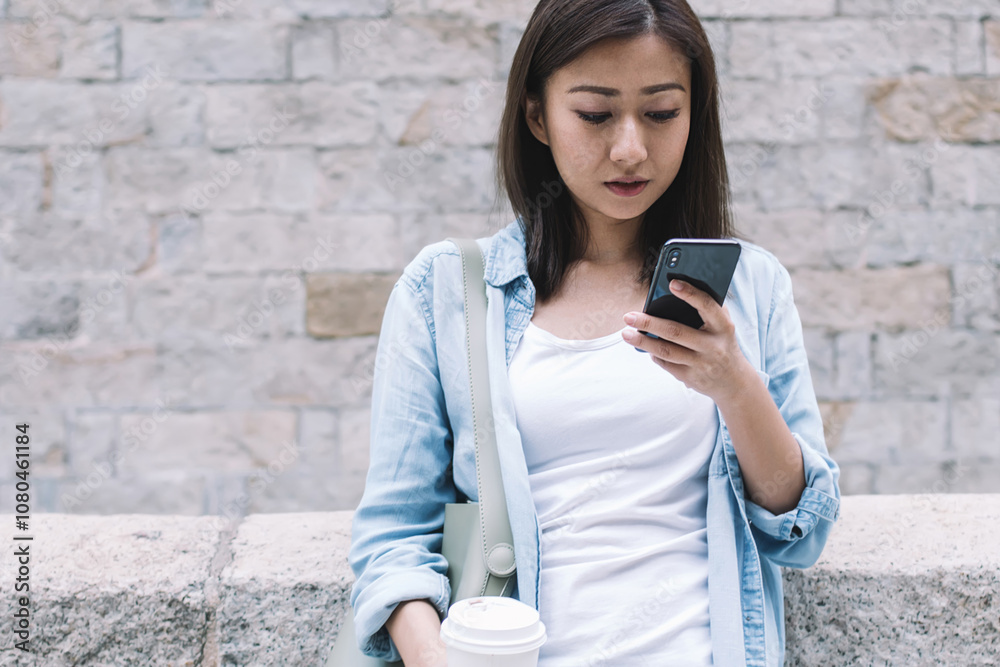 Fototapeta premium Pretty Asian woman texting and holding coffee