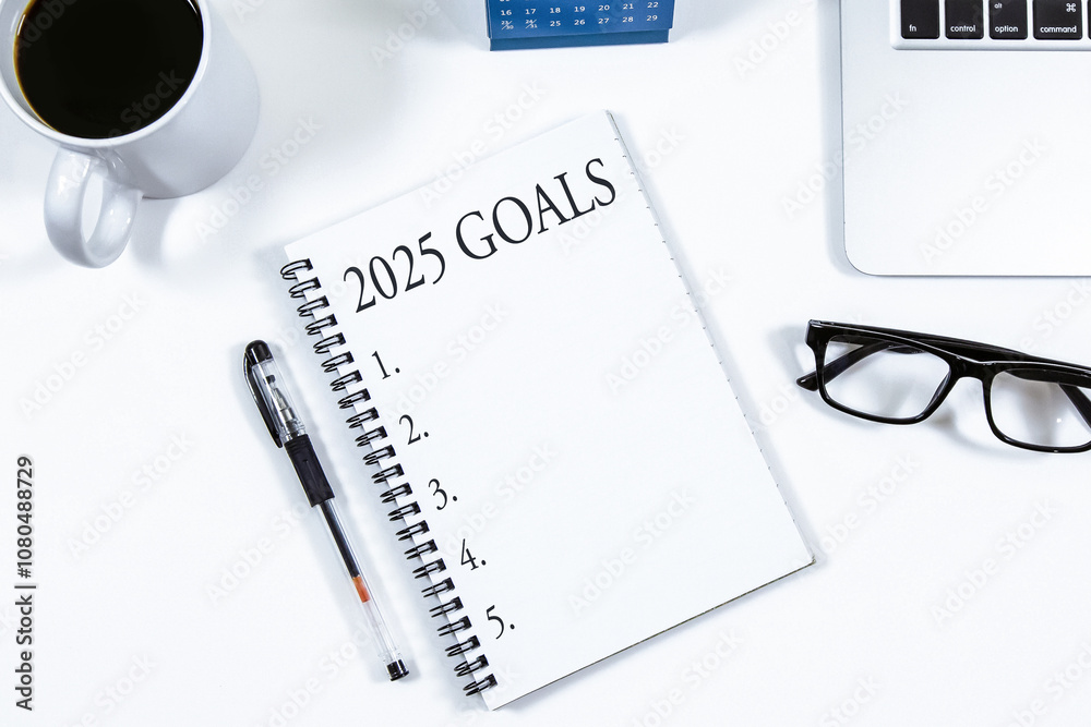 Top view of notebook handwriting goals for 2025 year, laptop and eyeglasses on white background. Business plan concept.