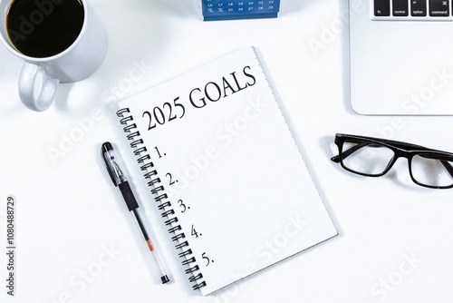 Obraz na płótnie Top view of notebook handwriting goals for 2025 year, laptop and eyeglasses on white background. Business plan concept. w salonie