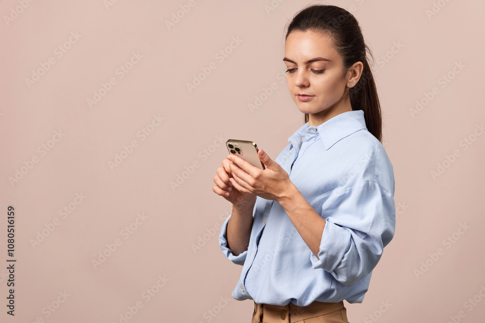 positive pretty woman using mobile phone looking at smartphone on beige background. copy space positive pretty woman using mobile phone looking at smartphone on beige background. copy space