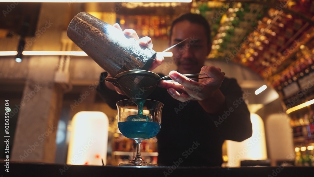 Closeup hand bartender using strainer mixed vodka in blue hawaii cocktail at luxurious counter. Preparation making special refresh drinks nightclub theme at nightclub on bokeh lighting warm. Vinosity. Closeup hand bartender using strainer mixed vodka in blue hawaii cocktail at luxurious counter. Preparation making special refresh drinks nightclub theme at nightclub on bokeh lighting warm. Vinosity.