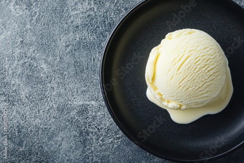 One perfectly round scoop of vanilla ice cream on a black plate, with minimal sauce drizzles for a refined dessert, [Minimalist food], [elegant dessert minimalism] photo