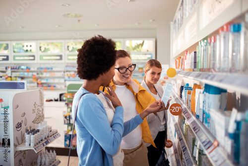 Pregnant woman browsing shelves with friends at pharmacy drug store