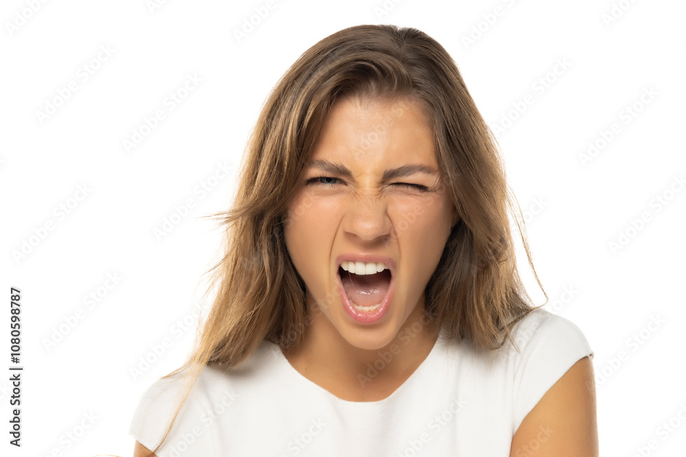 Portrait of young angry woman with a light makeup, screaming on a white studio background Portrait of young angry woman with a light makeup, screaming on a white studio background