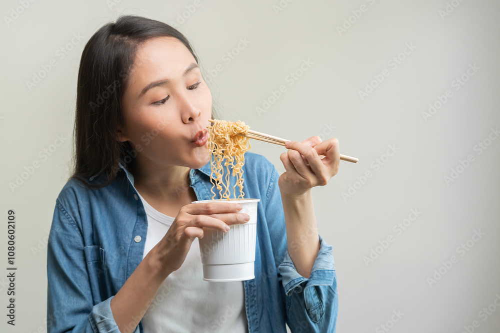 Happy temptation, attractive asian young student woman, cute girl using chopsticks eating instant ramen, noodles soup from a cup, cooking meal fast food lifestyle of traditional japanese person. Happy temptation, attractive asian young student woman, cute girl using chopsticks eating instant ramen, noodles soup from a cup, cooking meal fast food lifestyle of traditional japanese person.