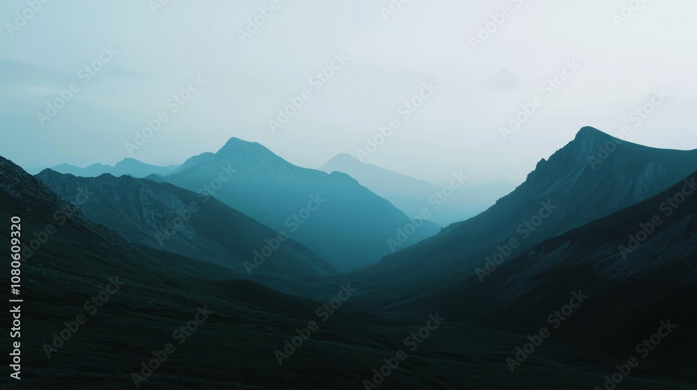 Fototapeta premium Tranquil mountain scene with misty valleys and towering peaks, captured at dawn under a serene blue sky.
