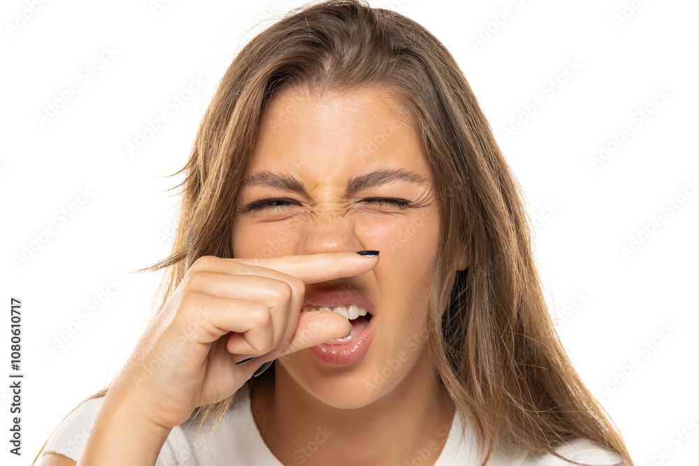 portrait of a young woman smelling a bad smell portrait of a young woman smelling a bad smell