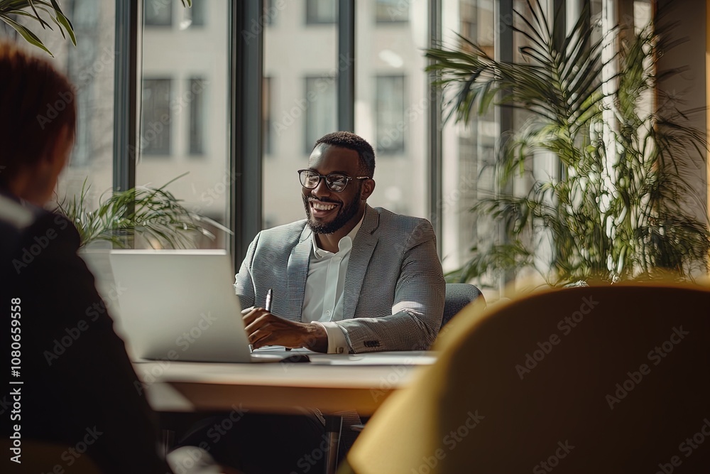 Smiling Man Working on a Laptop in a Modern Office With Large Windows and Greenery in the Early Afternoon Smiling Man Working on a Laptop in a Modern Office With Large Windows and Greenery in the Early Afternoon