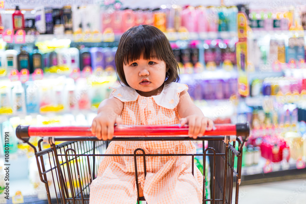 Cute girl sitting on a shopping cart in a shopping mall,Happy little ...