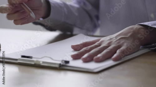 消しゴムで書類の文字を消す女性の手元