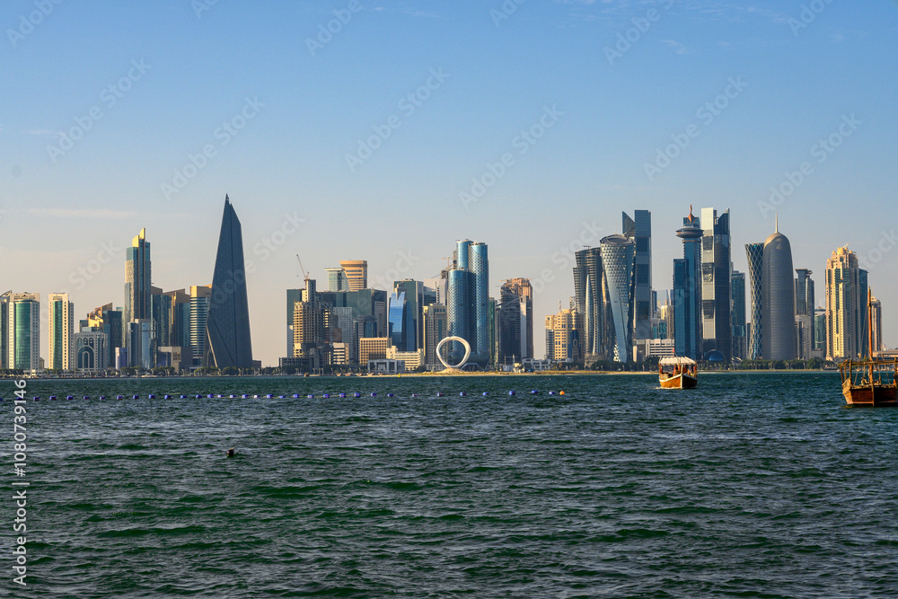 Obraz premium Beautiful seaside view of skyscrapers and boats in the sea in Doha, Qatar