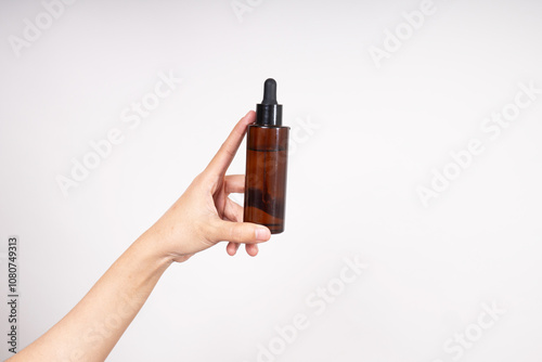 Woman hand holding unbranded bottle of serum, skin care and cosmetic concept, serum or cosmetic mockup photo