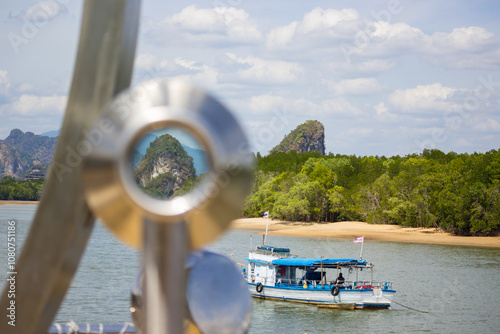 View of a limestone outcropping through a telescope eyepiece with a tour boat on a river in Thailand