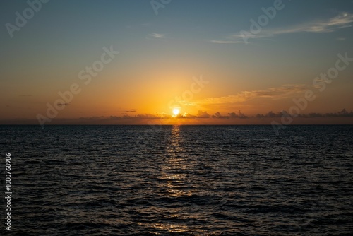 Serene ocean sunset with a vibrant orange sky and calm waves
