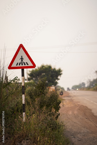 roadside pedestrian sign, rural safety road sign, pedestrian crossing ahead, countryside traffic sign, safety warning near road, triangular pedestrian symbol, highway pedestrian alert stock photo.