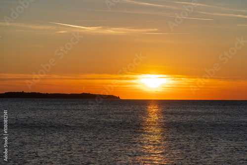 Piran, Slovenia - November 3, 2024: Sunset against the backdrop of a calm sea. The sun goes down behind the sea horizon.