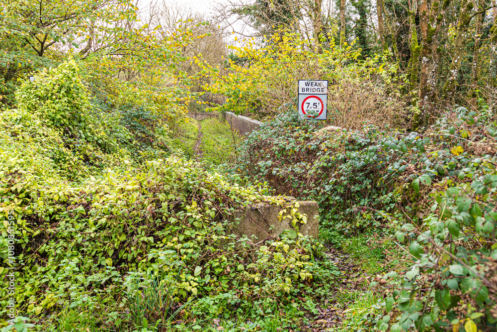 A weak road bridge closed to traffic over the disused Banbury and Cheltenham Direct Railway line near the Cotswold village of Hampen, Gloucestershire, England UK