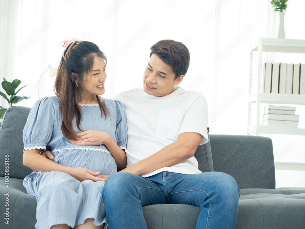 A happy Asian couple. Handsome husband and his beautiful wife pregnant sitting on sofa. A happy Asian couple. Handsome husband and his beautiful wife pregnant sitting on sofa.